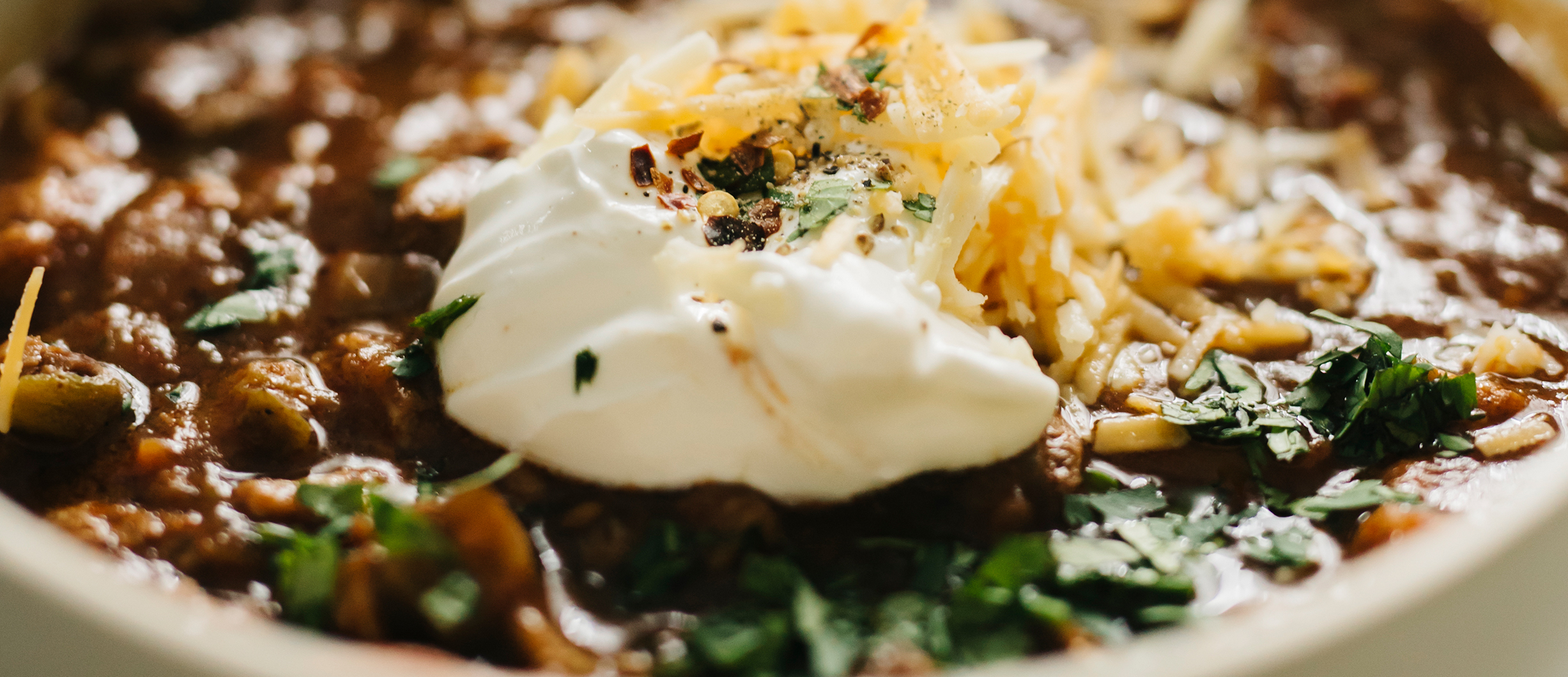 Chilli con carne with dollop of sour cream, herbs and cheese