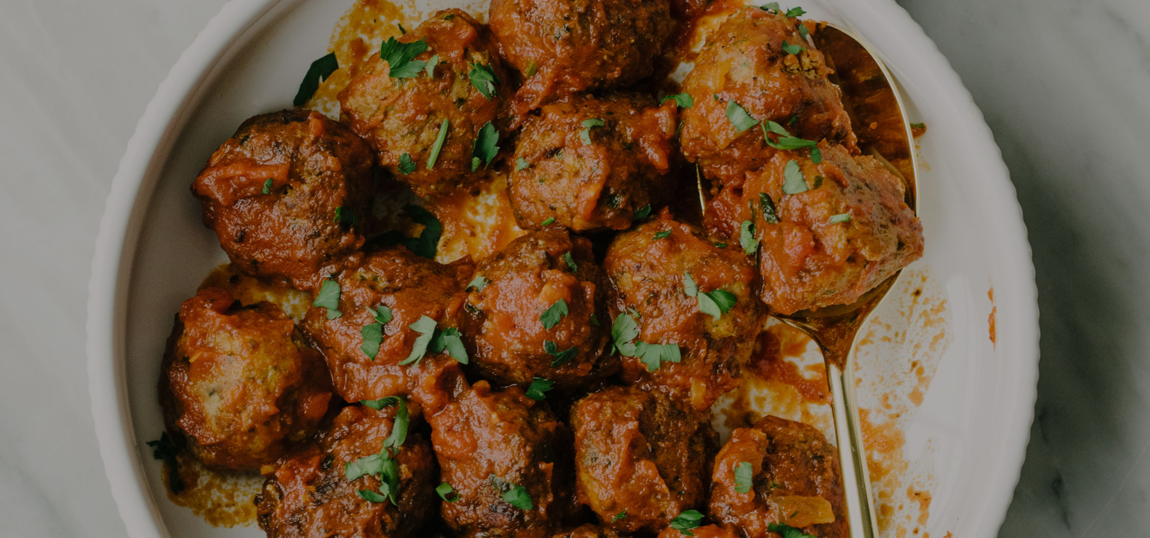 Flat-lay of Four Butchers meatballs in white bowl on blue napkin